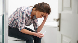 Teenage Girl Sitting In Bathroom With Pregnancy Test